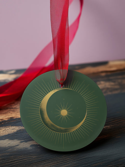 Round metal ornament featuring golden crescent moon and star design with Art Deco sunburst pattern on black background. 3.5-inch diameter piece with celestial motifs and crimson ribbon. Double-sided astronomical artwork.